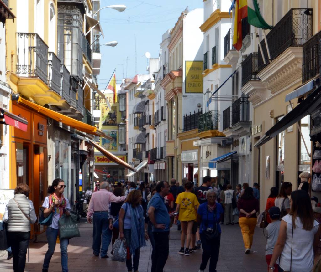an image of calle sierpes a street in seville spain, with people walking around and shopping