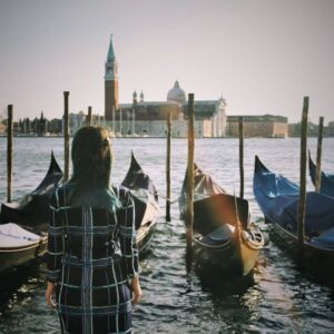 photo of a girl in front of gondolas on the sea in venice italy