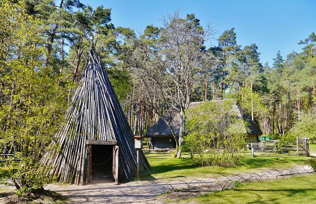 photo of ancient latvian hut with thatched cottage in the background