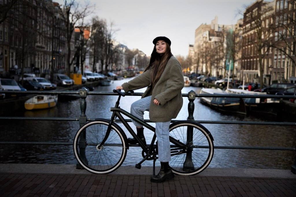 photo of a girl on a bike by a canal in amsterdam netherlands
