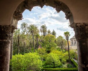 An image of a garden through a building arch in Seville Spain
