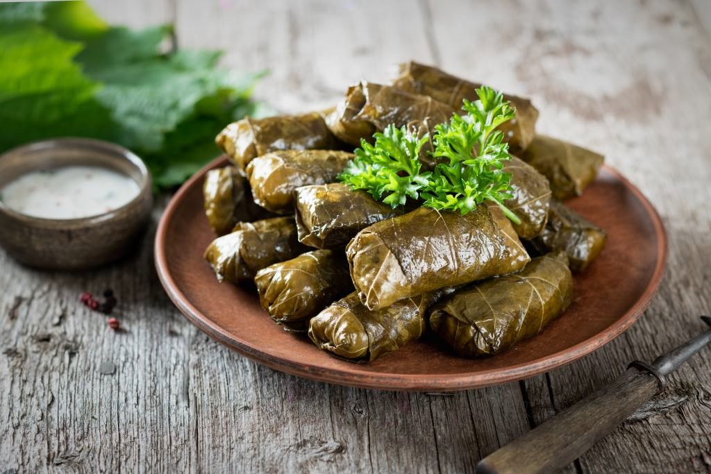 photo of a brown plate of dolmades - green stuffed vine leaves