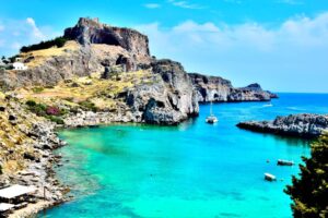photo of an ocean lagoon with a boat and cliffs in rhodes greece