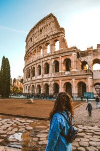 an image of the Colosseum in rome italy with a girl in the foreront looking at it