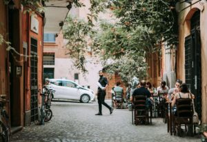 a photo of a street in rome italy with some people sitting at small tables