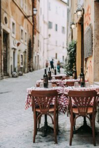 a photo of a street in rome italy with some tables with bottles of wine on them