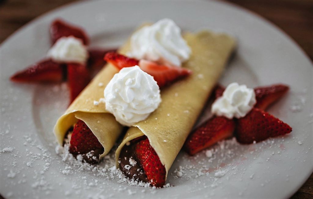 photo of a plate of Palatschinken crepes in vienna austria with cream and strawberries