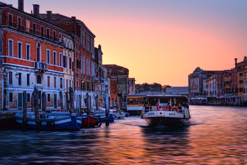 photo of a boat in a canal in venice italy at sunset