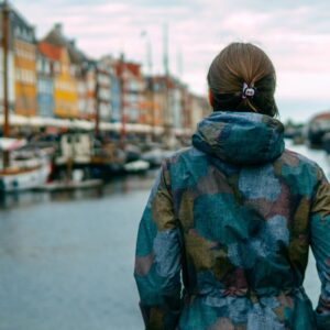 photo of a girl in blue coat looking at river in copenhagen denmark