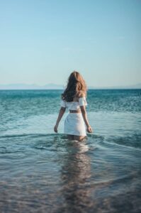 a picture of a woman wading out into the sea