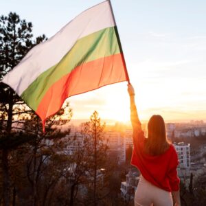 photo of woman holding a bulgarian flag at sunset