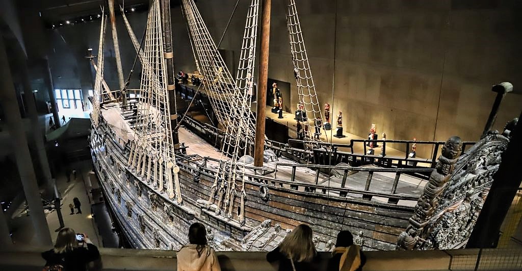 photo of people looking at a wooden ship in a museum in sweden