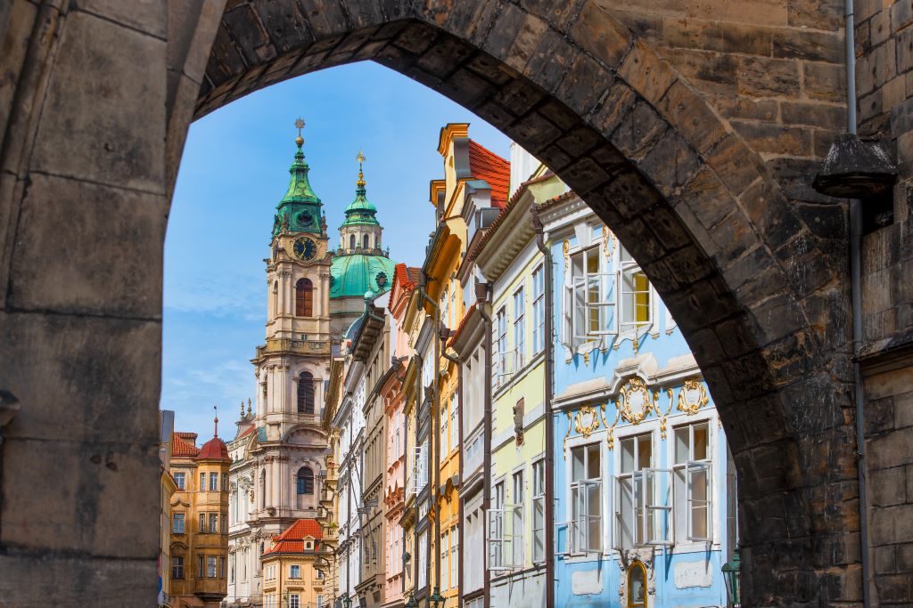 photo of a street in prague with a stone arch