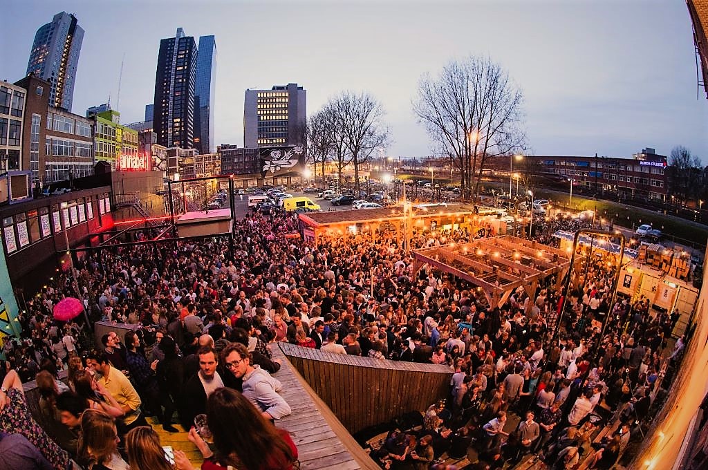 photo of a large crowd at an outdoor bar in rotterdam netherlands