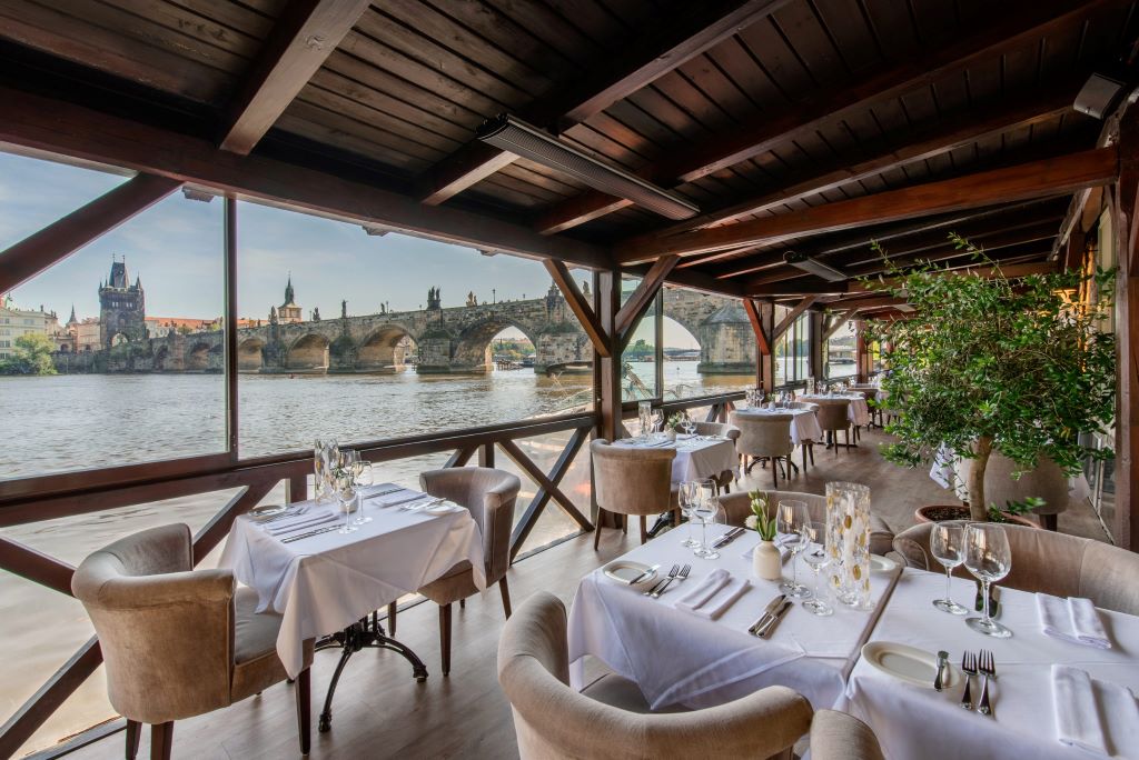 photo of a restaurant with a view of a bridge and river in prague czech republic