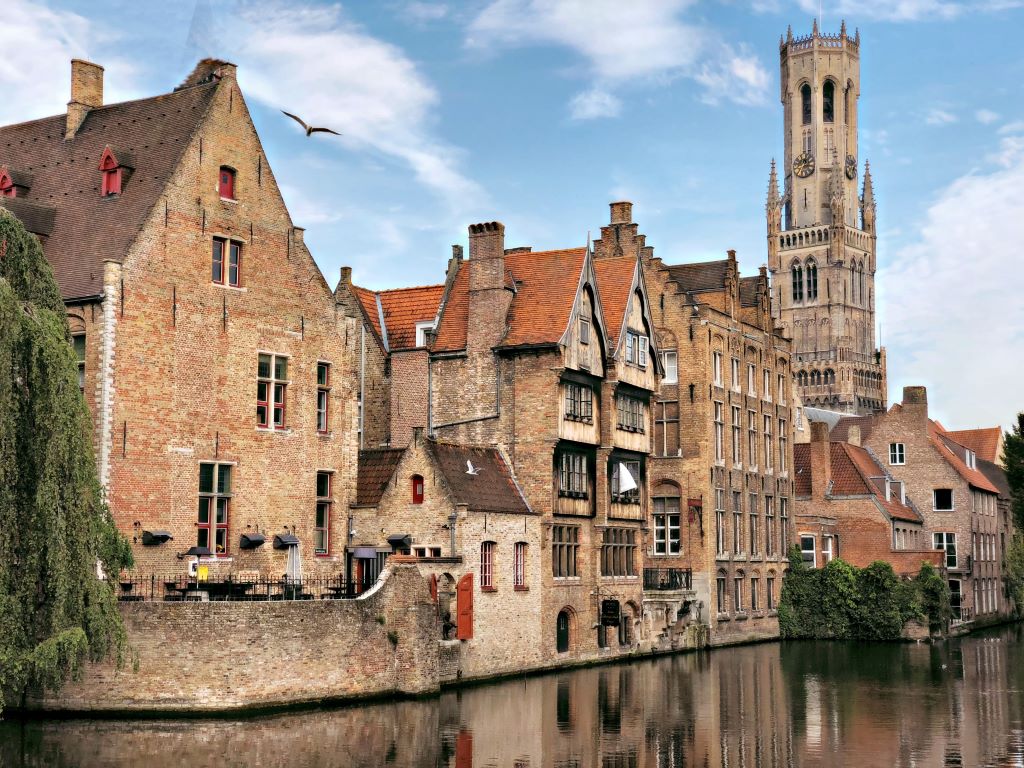 photo of houses and tower by water in bruges belgium