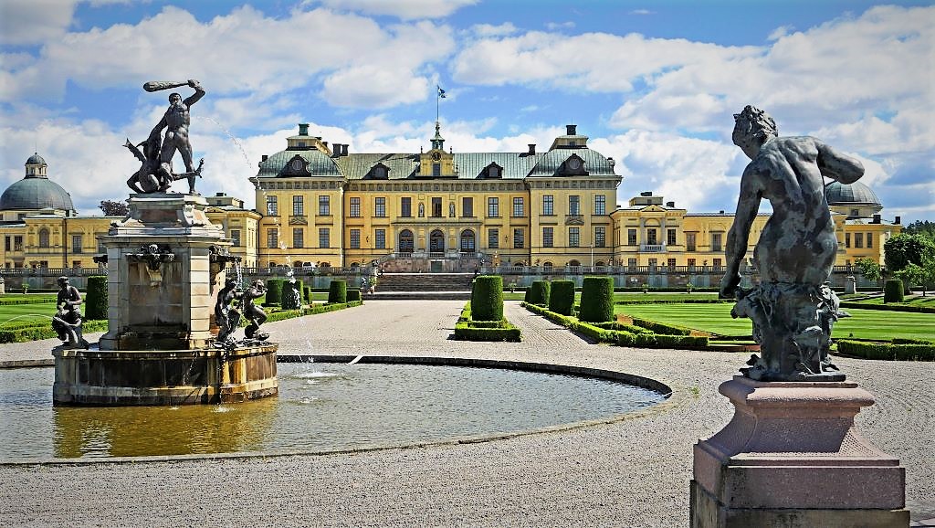 photo of a yellow palace with grey statues in stockholm sweden