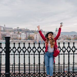 photo of a lady in red jacket with hands up on a bridge