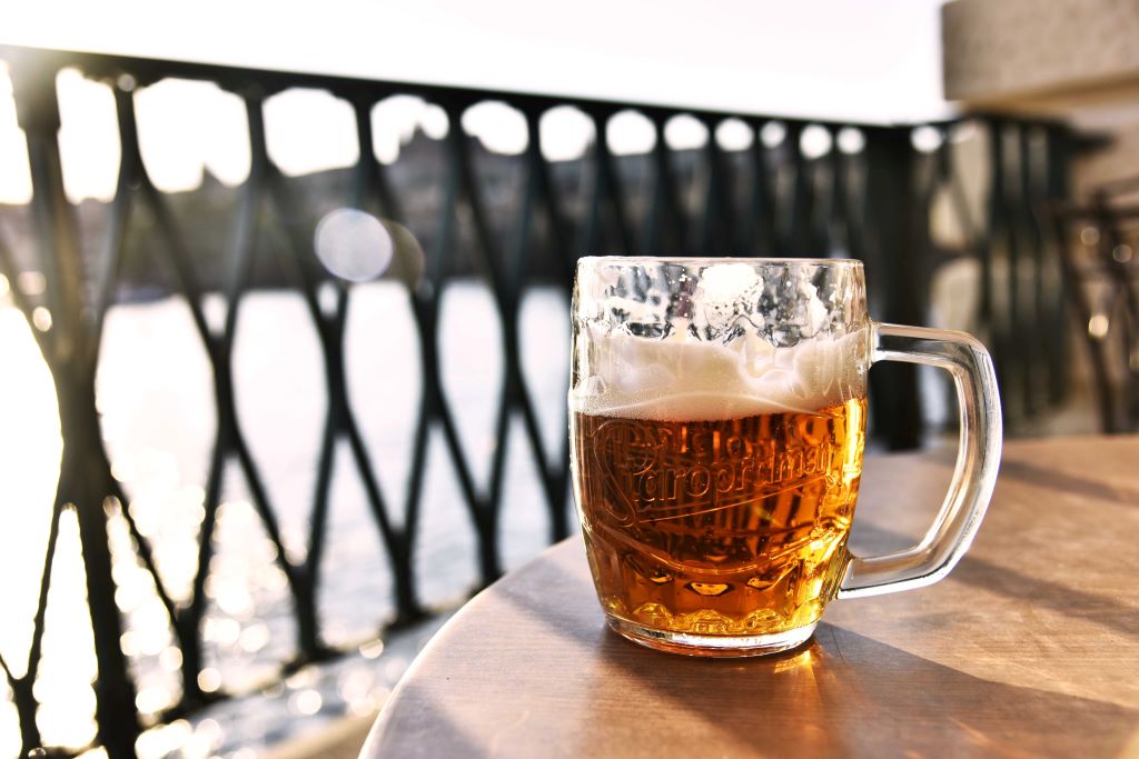 photo of pint of beer sitting on table by water in prague czech republic